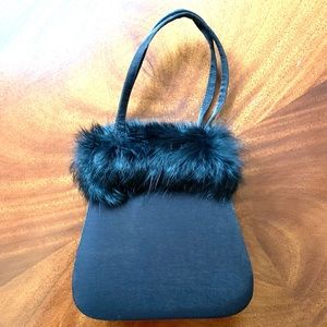 Black satin like elegant clutch purse with fur trim. Shoulder strap of hand.